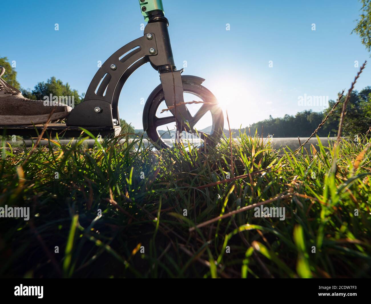 Gros plan du pneu de roue avant du scooter de poussée stationné au lac en soirée d'été. Fin de plaisir et rentrer à la maison au lit. Banque D'Images