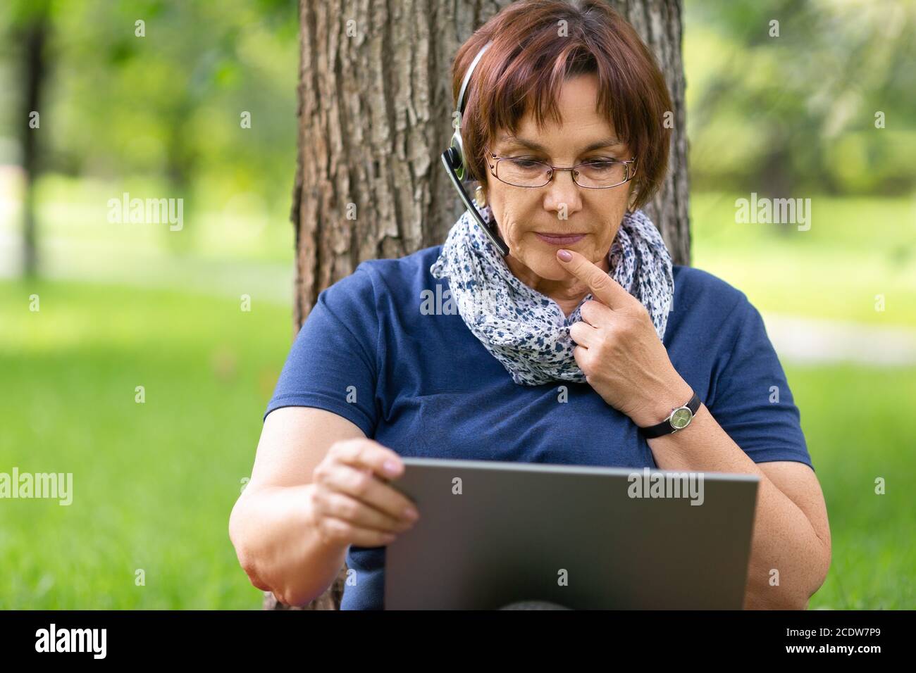 Femme âgée travaillant à distance sur un ordinateur portable dans le ...