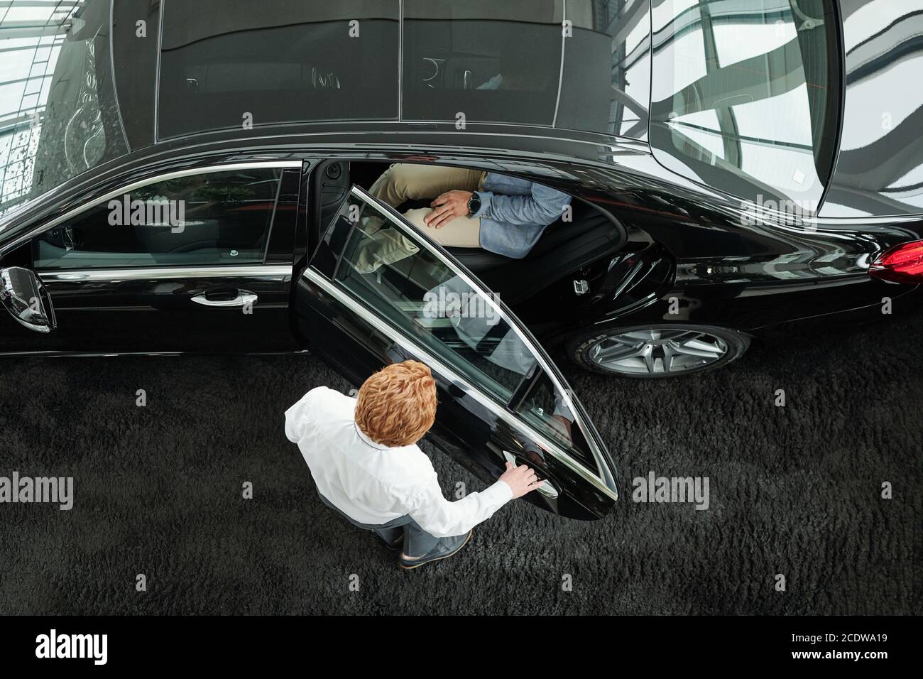 Le directeur des ventes ferme la porte de la voiture avec les clients à l'intérieur avant l'essai de conduite Banque D'Images