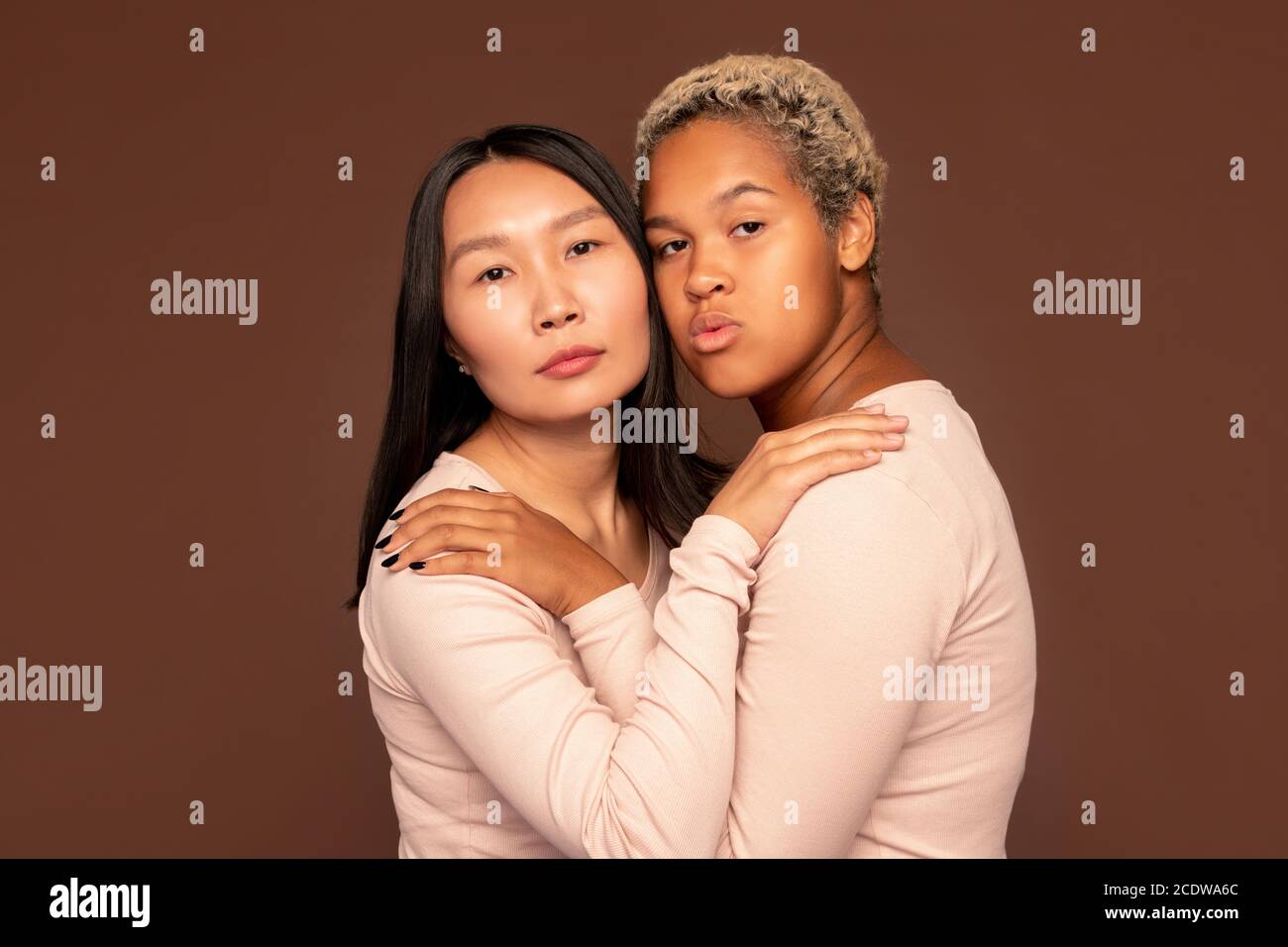 Deux jeunes femmes relativement interculturelles se gardant la main l'une sur l'autre épaules Banque D'Images