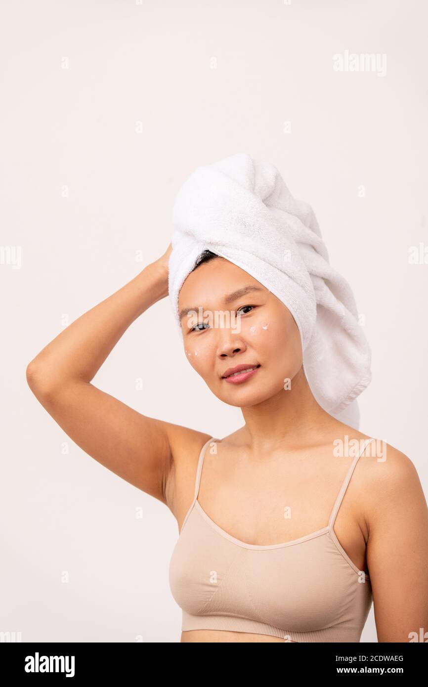 Jeune jolie femelle d'origine asiatique avec une serviette sur la tête et une table de cuisson beige Banque D'Images