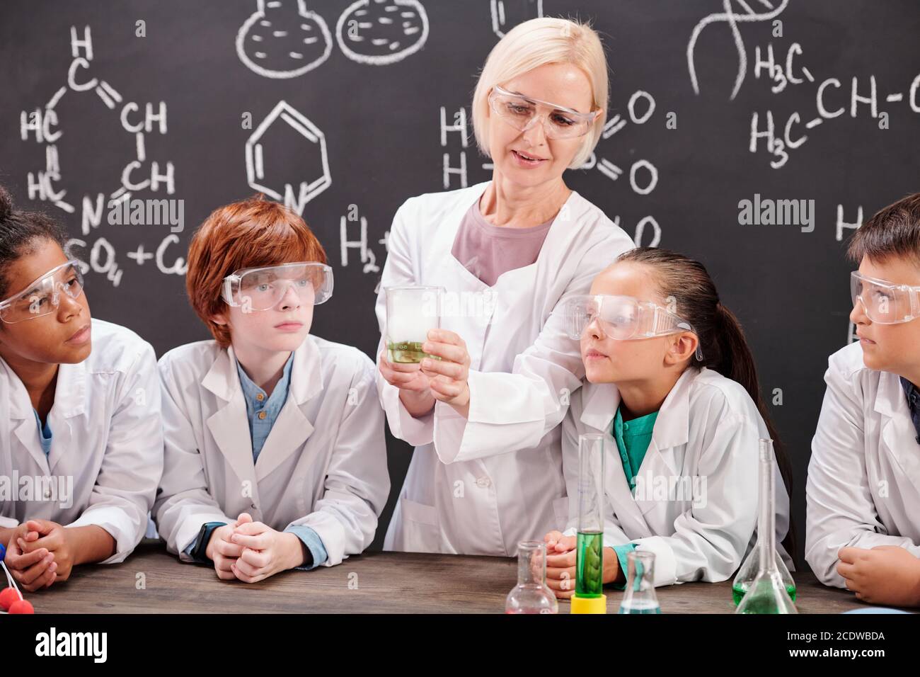 Jeune professeur de chimie montrant son mélange de deux élèves substances chimiques Banque D'Images