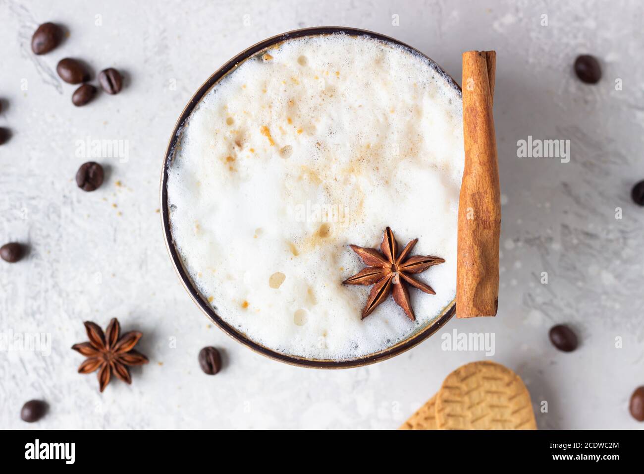 Tasse de café noir ou de cappuccino avec mousse de lait décorée avec étoile anis et bâton de cannelle sur la table lumineuse avec biscuits au pain d'épice et coff rôtis Banque D'Images