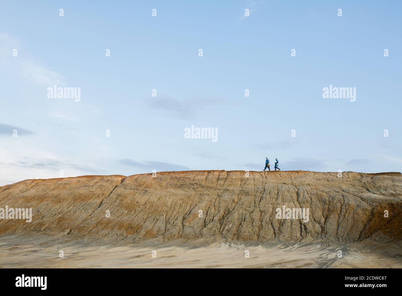 Petites silhouettes de chercheurs dans des combinaisons de protection se déplaçant sur le dessus de la colline Banque D'Images