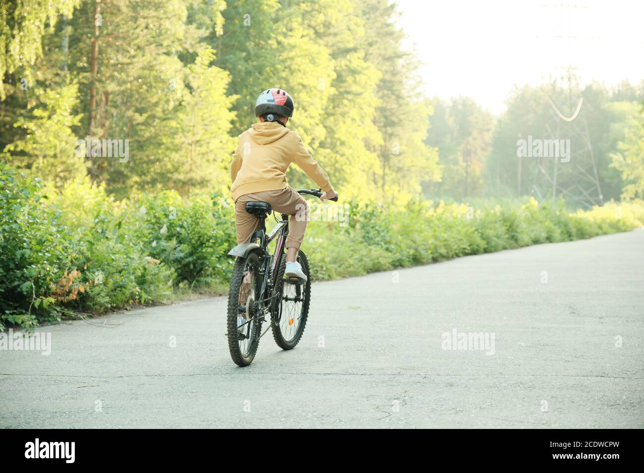 Vue arrière d'un écolier contemporain dans un casque de protection à vélo Banque D'Images