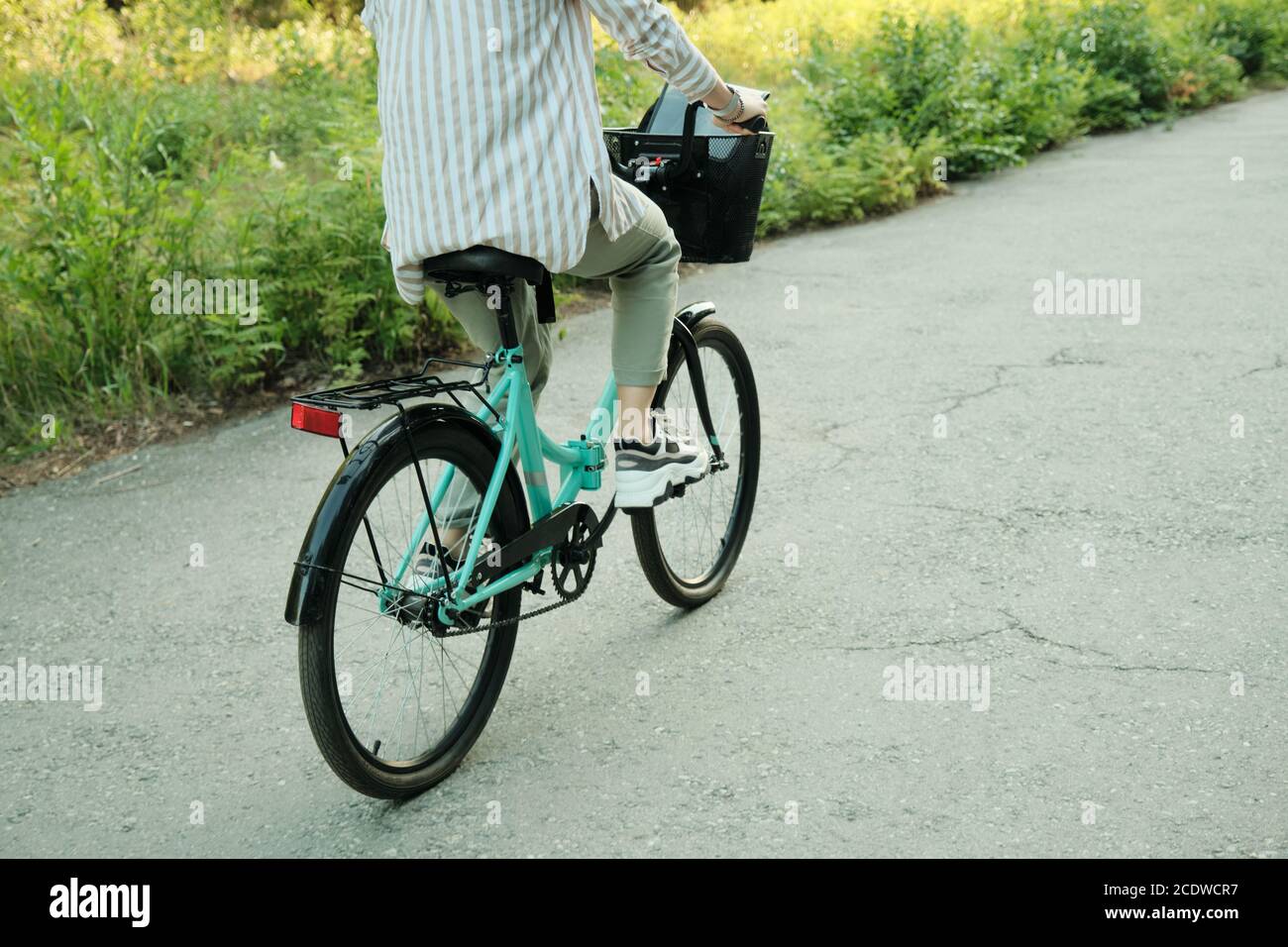 Vue arrière de la jeune femme active assise à vélo et descendre la route asphaltée Banque D'Images
