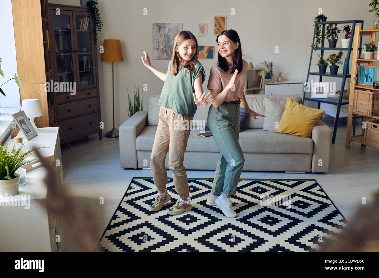 Jeune femme gaie brune et sa joyeuse fille adolescente dansant ensemble Banque D'Images