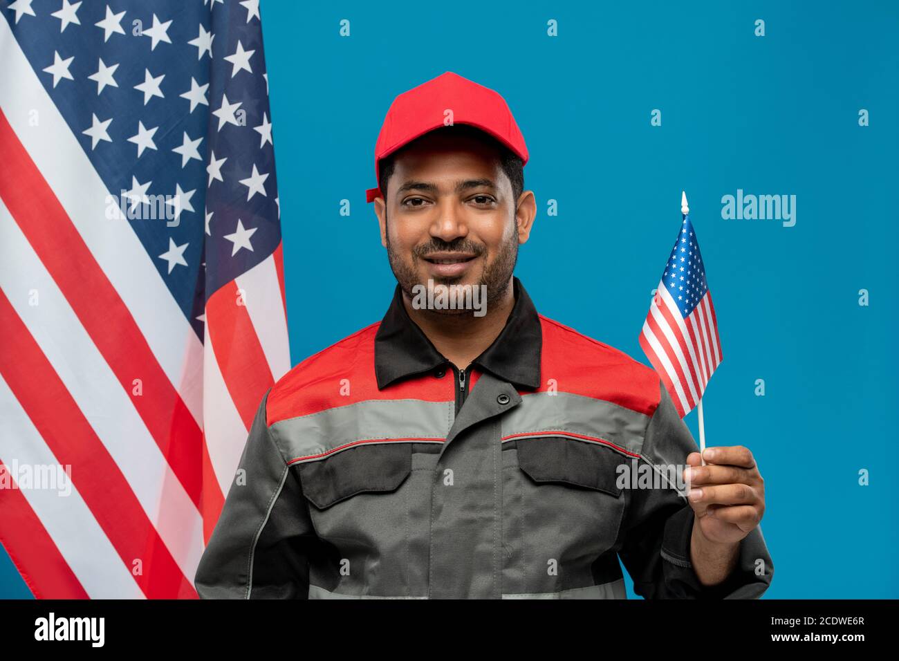Un jeune travailleur ou réparateur heureux d'origine hispanique qui tient petit drapeau Banque D'Images