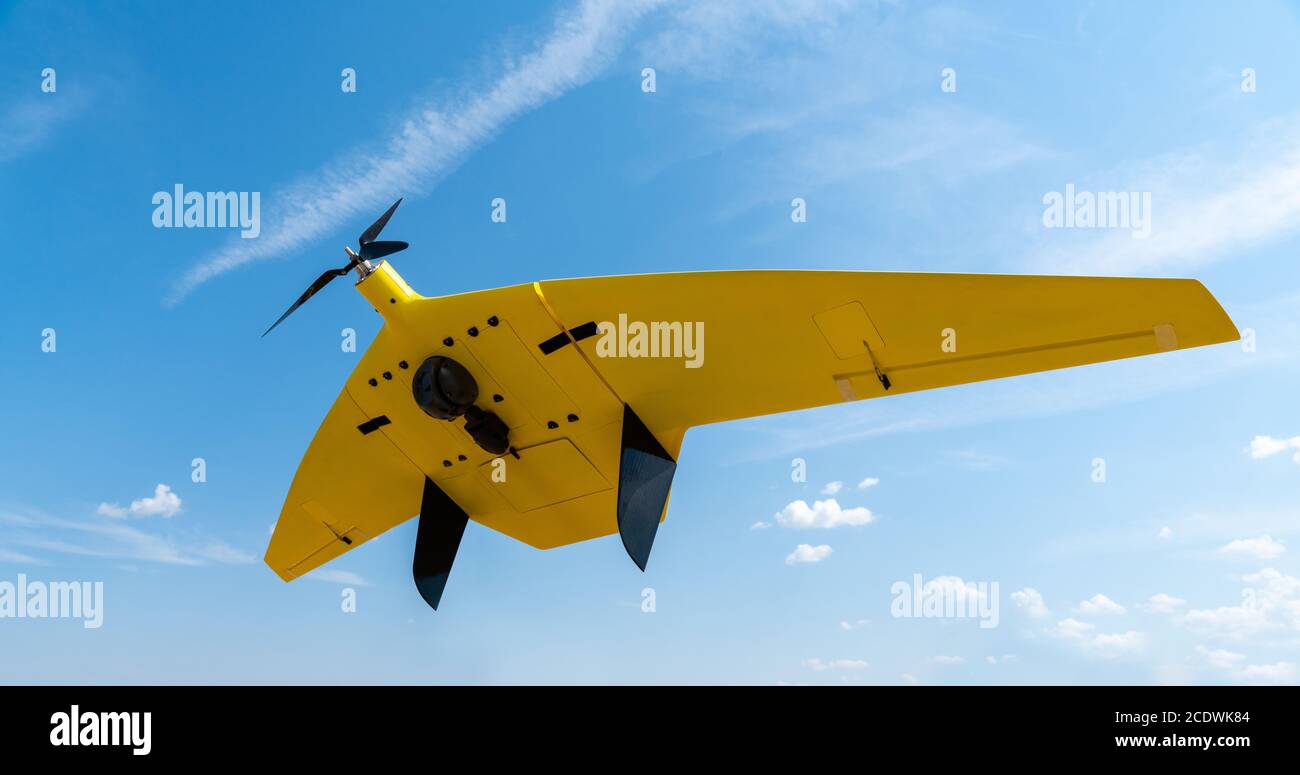 Un drone jaune avec un appareil photo vole dans le ciel bleu Banque D'Images