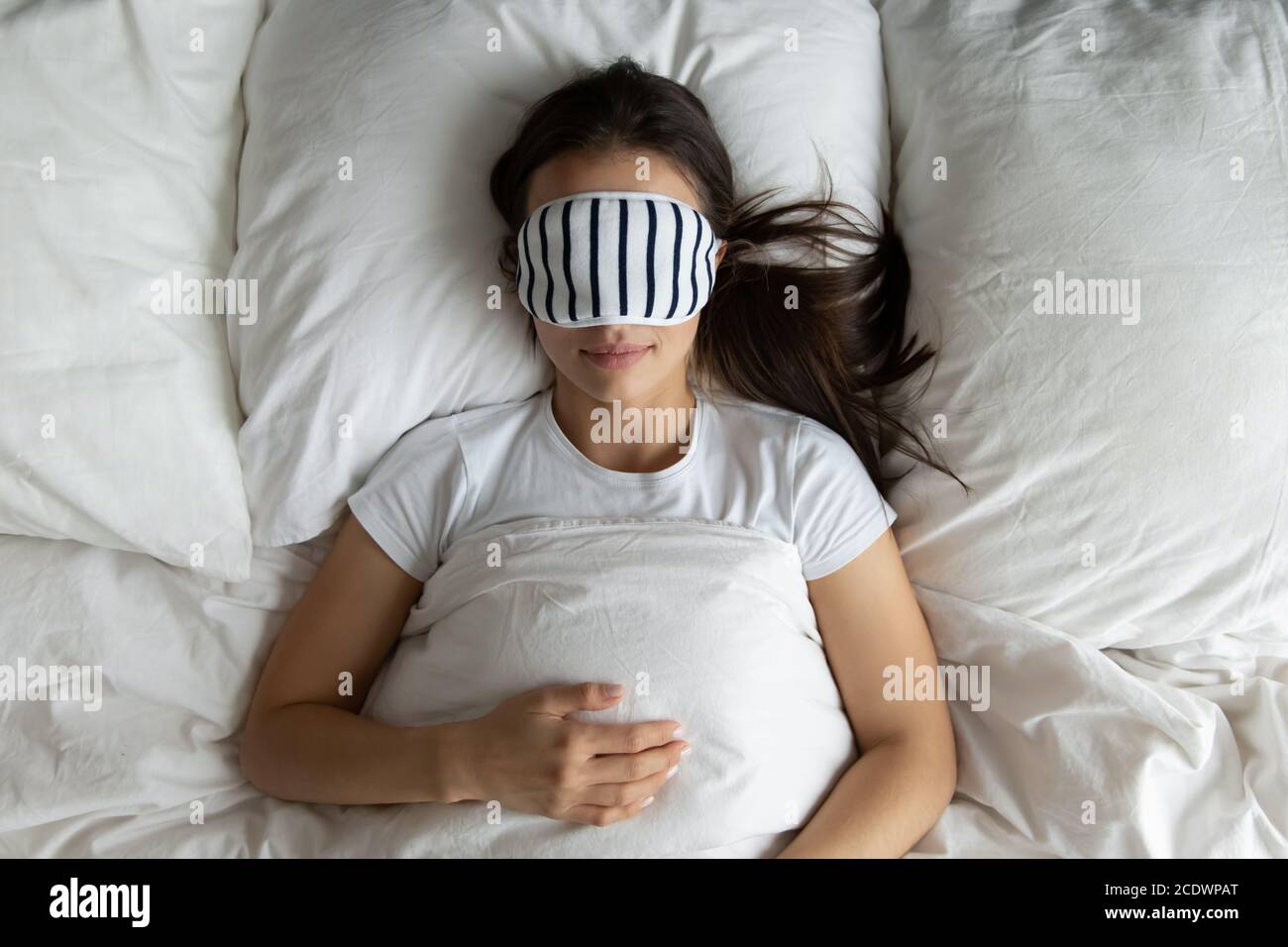 Vue de dessus paisible jeune femme portant un masque dormant dans le lit Banque D'Images