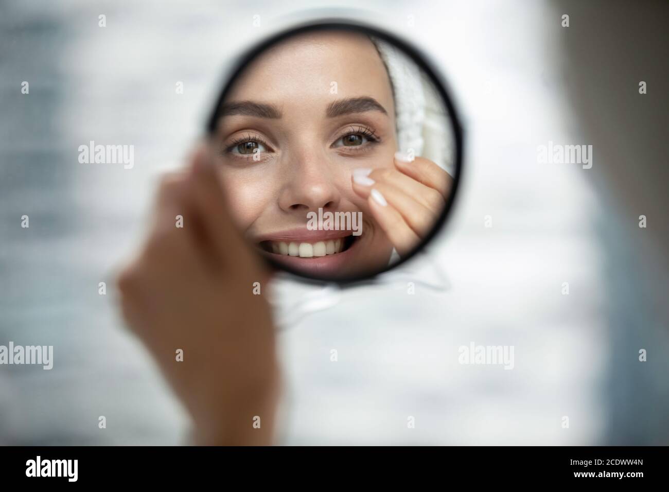 Gros plan souriant belle femme regardant dans un petit miroir rond Banque D'Images