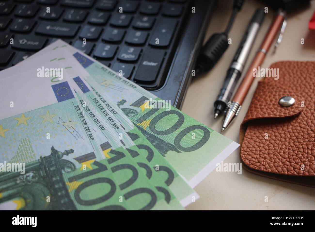 Beaucoup de 100 euros sur le clavier d'ordinateur portable, deux stylos, portefeuille. Concept d'entreprise en ligne Banque D'Images