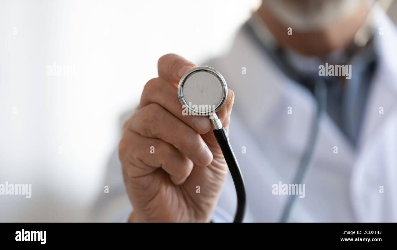 Gros plan médecin mature tenant le stéthoscope, contrôle médical Banque D'Images