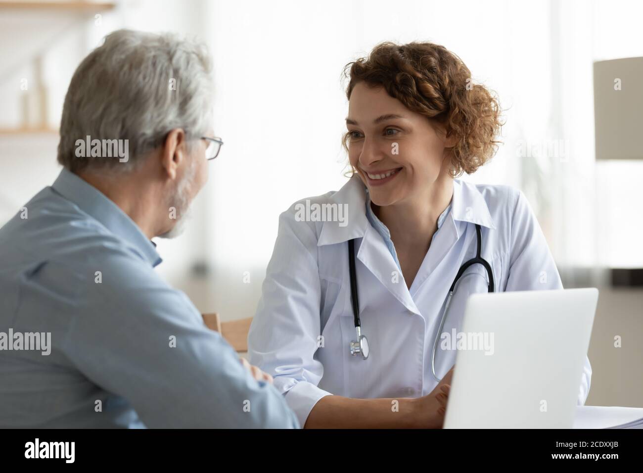 Femme souriante médecin à l'écoute des plaintes de patients matures lors de la réunion Banque D'Images