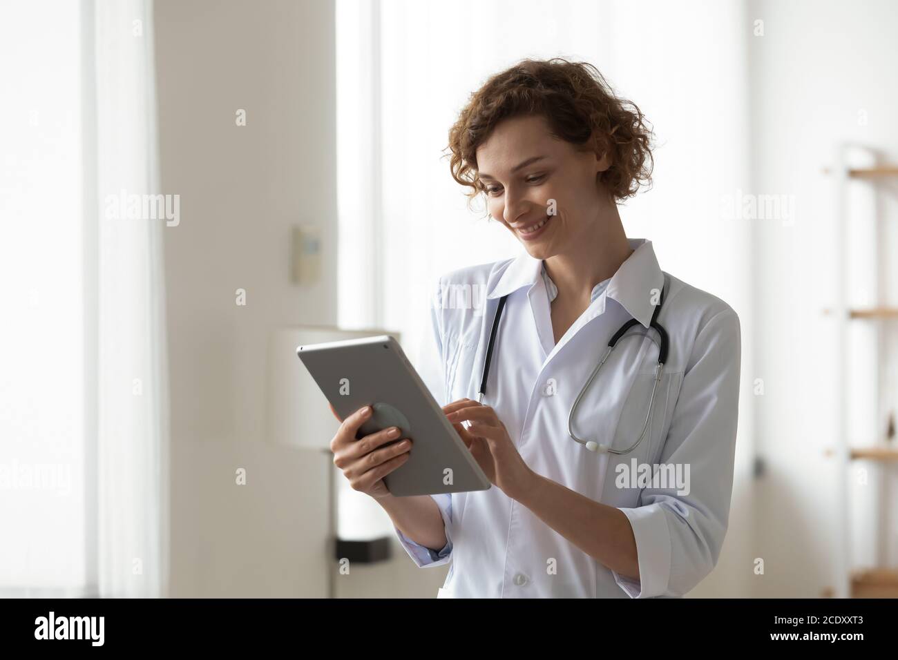 Femme souriante médecin professionnel utilisant une tablette numérique, debout au bureau Banque D'Images