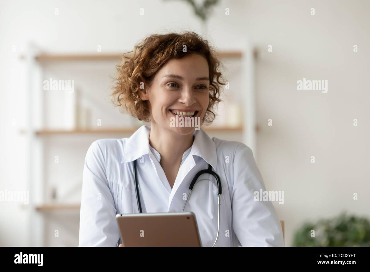 Femme souriante médecin tenant une tablette numérique, travaillant en ligne à l'hôpital Banque D'Images