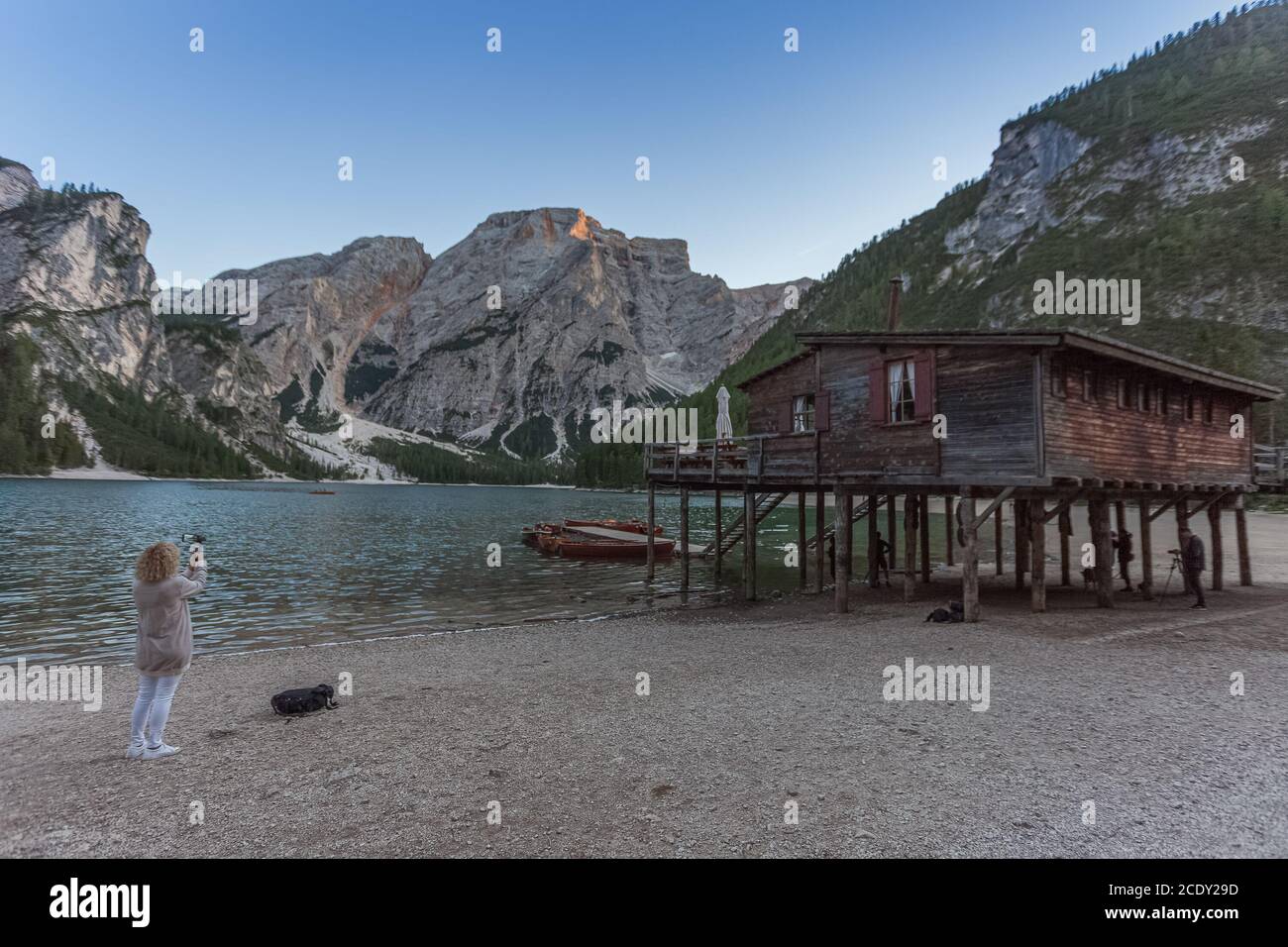 Femme brésilienne blonde Prenez la photo de la maison devant les eaux cristallines du lac Braies, Tyrol du Sud, Italie Banque D'Images