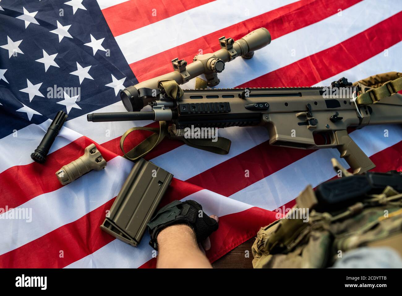 Gros plan d'un soldat méconnaissable debout à bord d'un fusil remonté sur un américain drapeau Banque D'Images