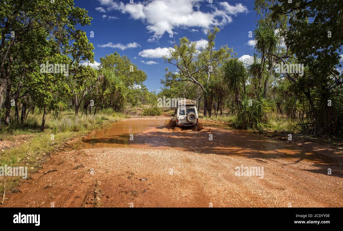 Australie occidentale – route de gravier de l'Outback inondée avec une voiture 4x4 traversée du trou d'eau à la savane Banque D'Images