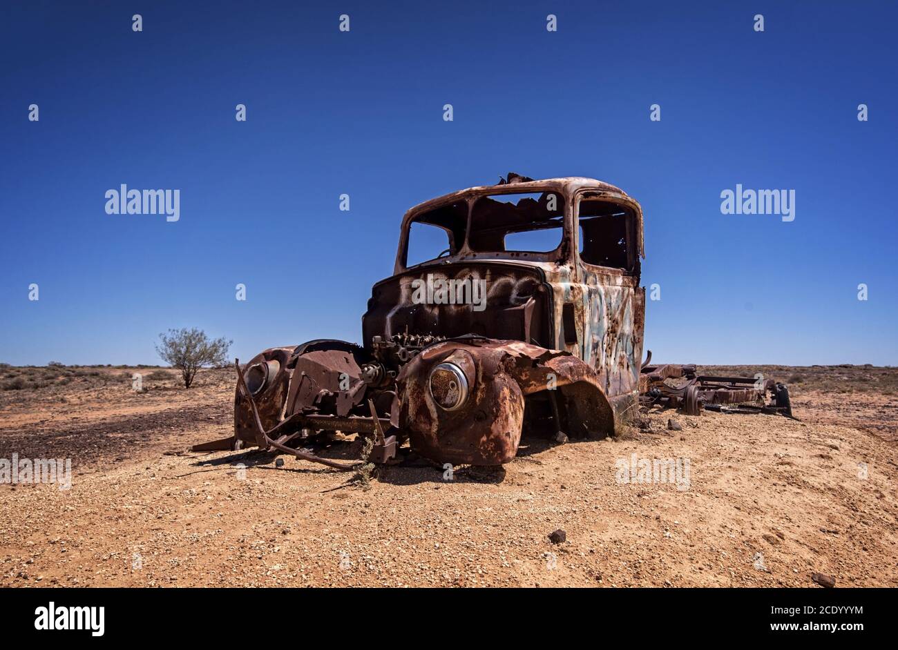 Australie – désert de l'Outback avec une vieille voiture abandonnée près de la piste sous ciel bleu Banque D'Images