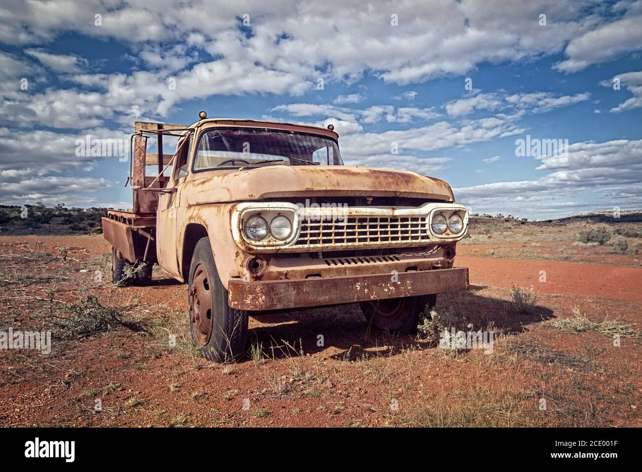Australie – désert de l'Outback avec une vieille voiture abandonnée près de la piste sous ciel nuageux Banque D'Images