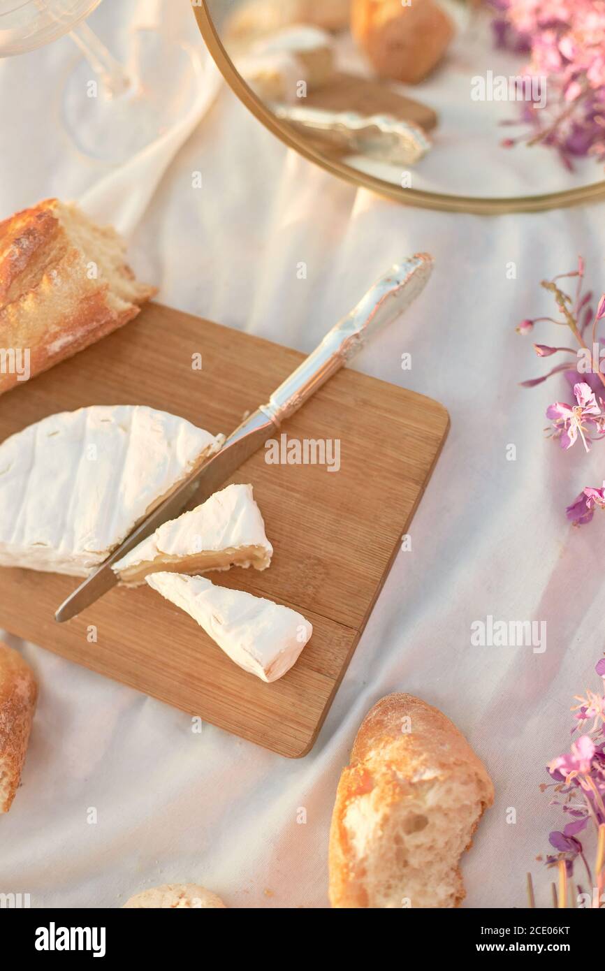 Été - pique-nique. brie au fromage, baguette, pêches, champagne, mirule, fleurs et panier Banque D'Images