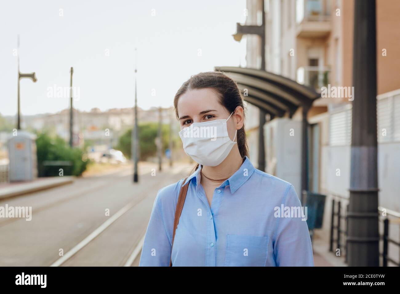 Photo d'une jeune femme portant un masque facial à une station d'attente du tramway. Nouveau concept normal Banque D'Images