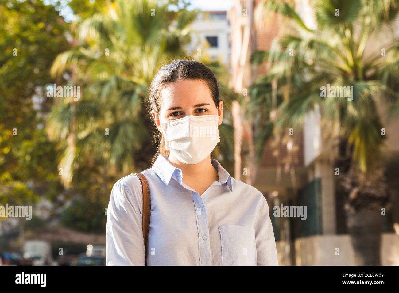 Photo d'une jeune femme portant un masque regarder un appareil photo dans la rue par beau temps Banque D'Images