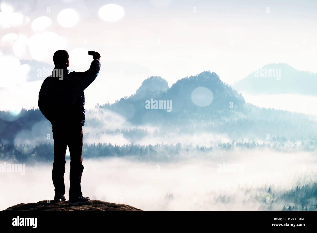Grain du film. Le grand touriste prend le selfie sur le sommet au-dessus de la vallée. Photographie sur smartphone Banque D'Images