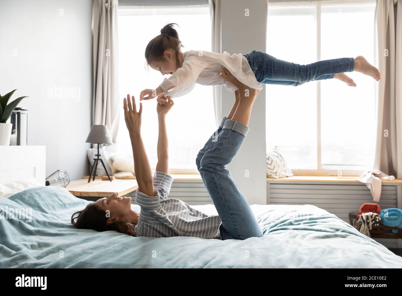 Jeune maman souriante tenant la petite fille sur les jambes droites. Banque D'Images