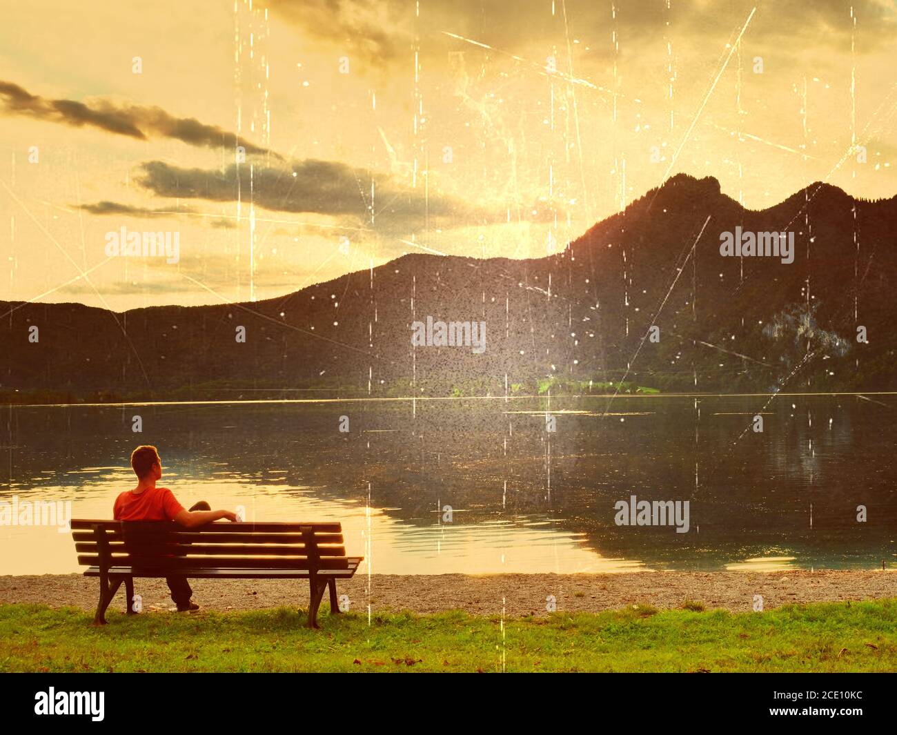 Effet de film. Seul l'homme est assis sur un banc à côté d'un lac de montagne azur. L'homme se détendre et observer les hauts sommets des Alpes au-dessus du lac M. Banque D'Images