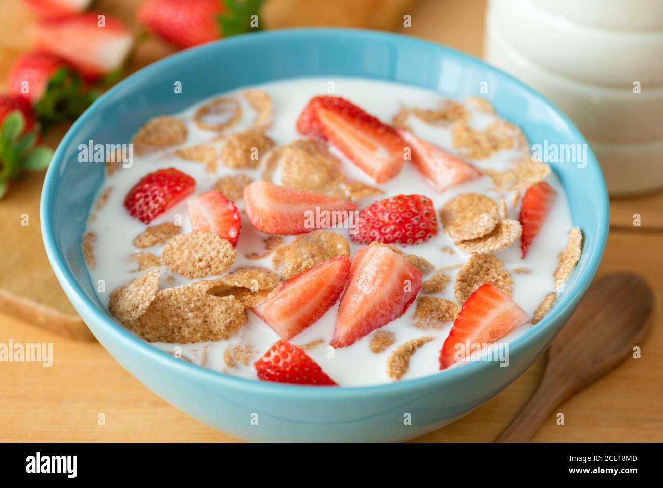 Flocons de grains entiers avec son de blé, fraises et lait d'amande dans un bol bleu pour un petit déjeuner sain Banque D'Images