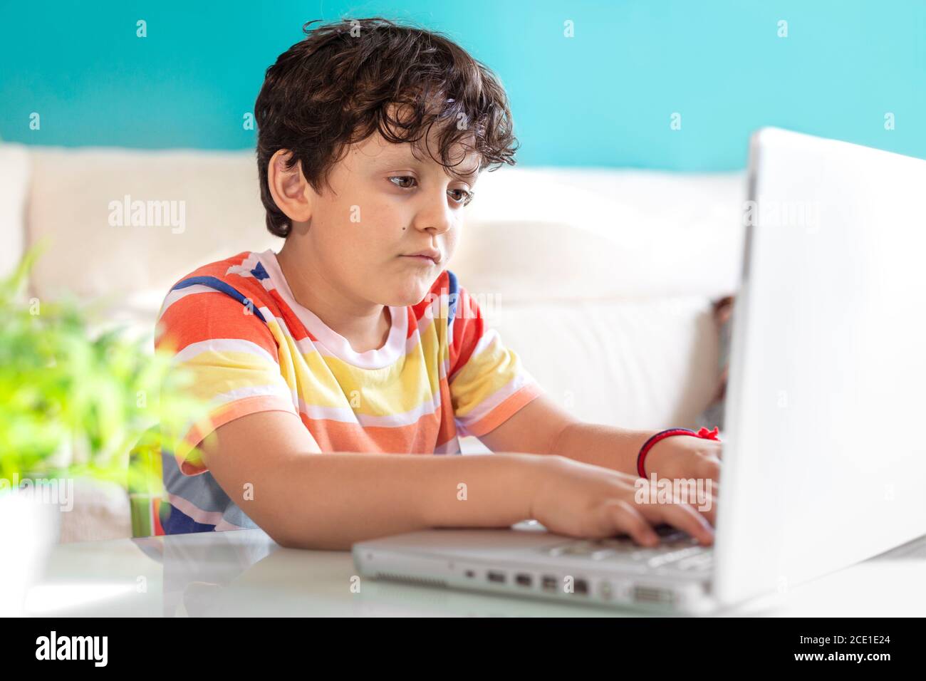 Petit garçon utilisant un ordinateur portable à la maison. Concept de technologie moderne et d'éducation en ligne. Banque D'Images