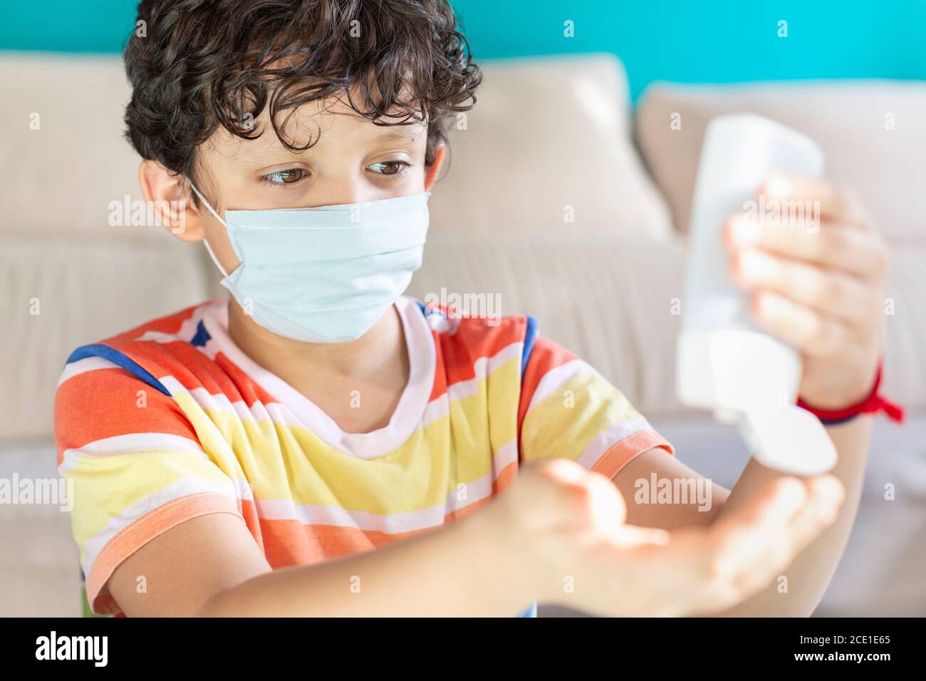 Petit garçon avec un masque facial appliquant du gel hydroalcoolique sur Ses mains comme mesure préventive pendant la pandémie de Covid-19 Banque D'Images
