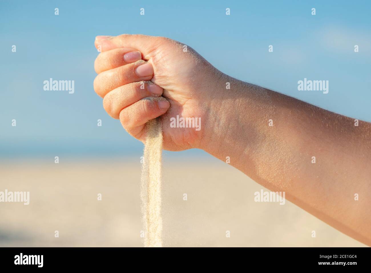 Gros plan sur le sable qui coule de la main sur la plage par une belle journée d'été. Jouer avec le sable en vacances. Banque D'Images