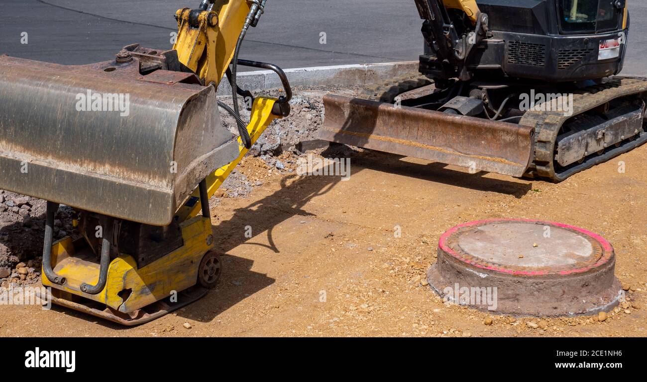 Pelle hydraulique de génie civil sur un chantier de construction de trottoirs Banque D'Images