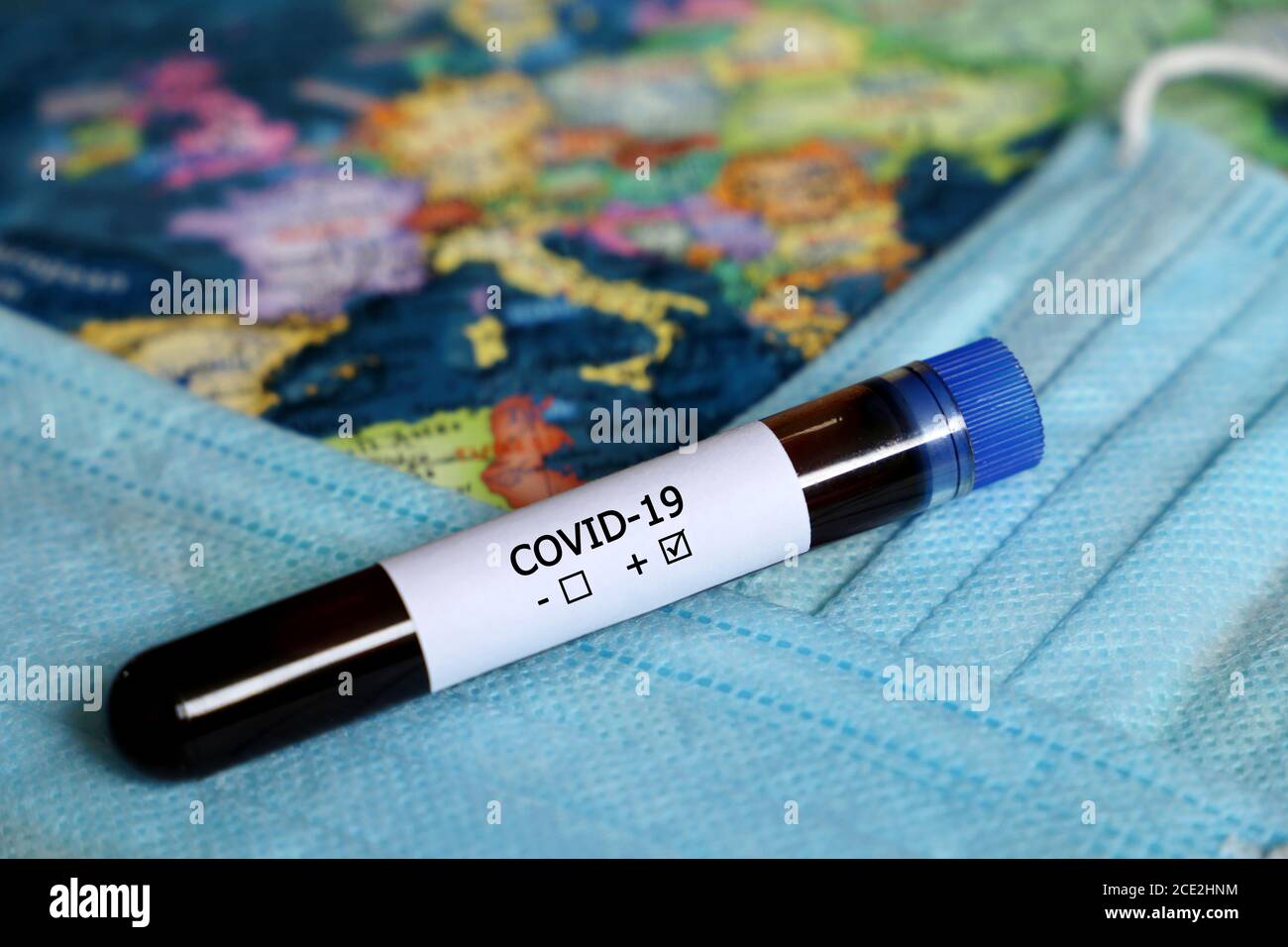 Tube à essai avec échantillon de sang Covid-19 sur la carte de l'Europe et masque médical de fond. Test positif du coronavirus, pandémie dans l'UE Banque D'Images