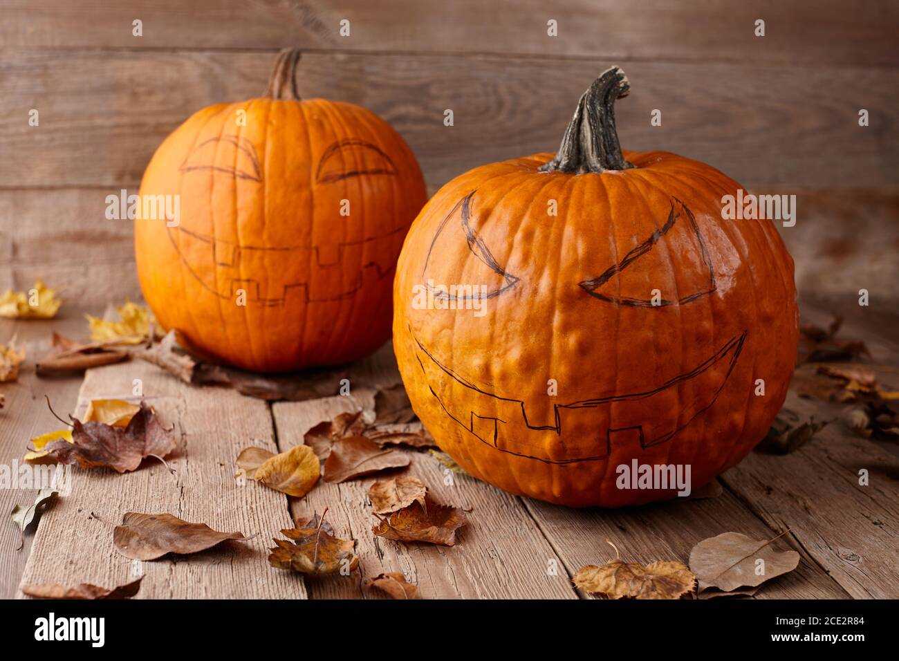 Citrouilles aux visages effrayants dessinés sur des planches en bois. Fabrication de lanternes de type Jack-o-lanternes pour Halloween. Banque D'Images