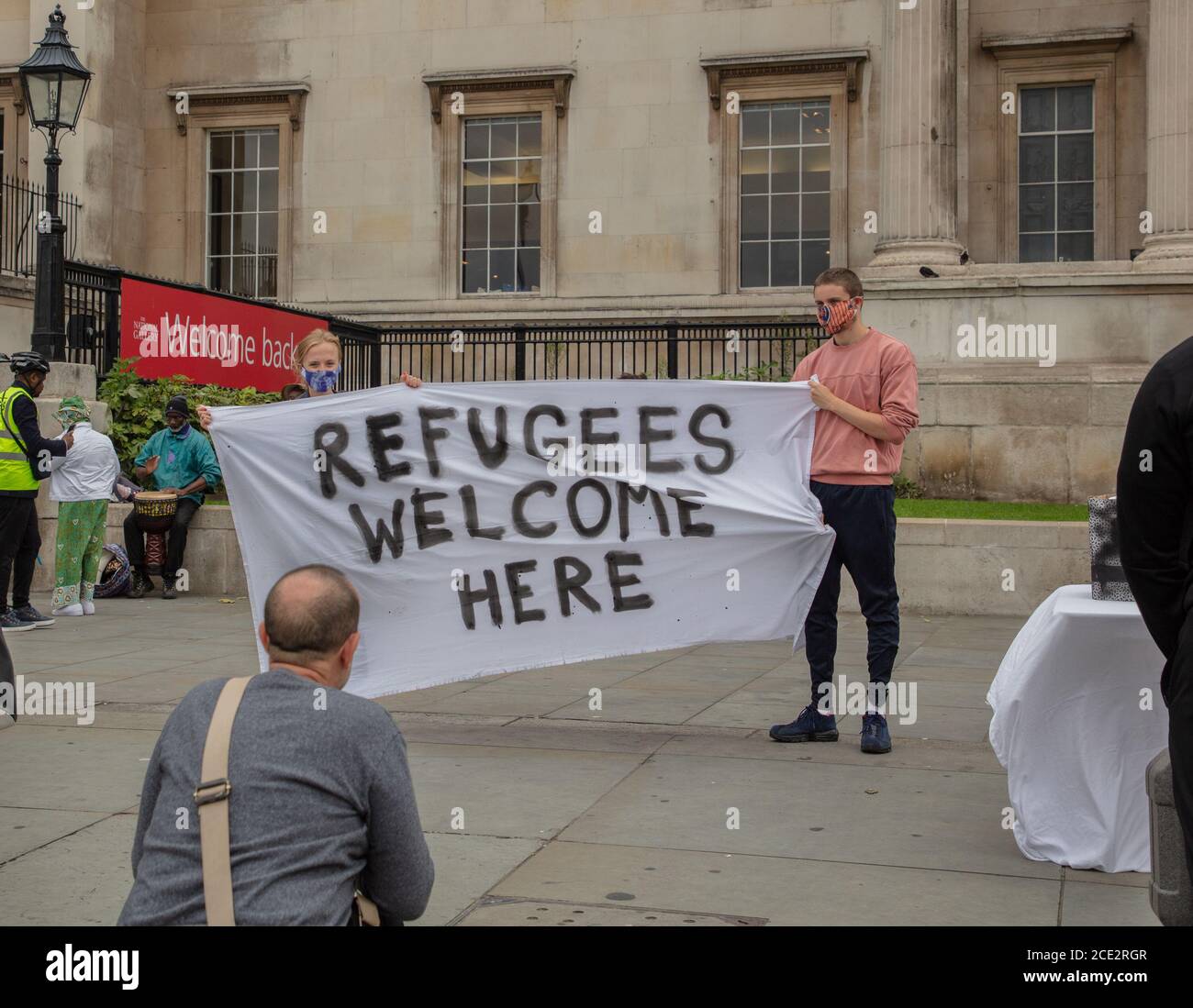 Londres, Royaume-Uni. 30 août 2020. Deux jeunes manifestants tiennent une bannière « les réfugiés sont les bienvenus ici », devant la National Gallery London, sur Trafalgar Square, qui accueille les visiteurs pendant la pandémie du coronavirus ( Covid-19). Credit: Joe Kuis / Alamy News Banque D'Images
