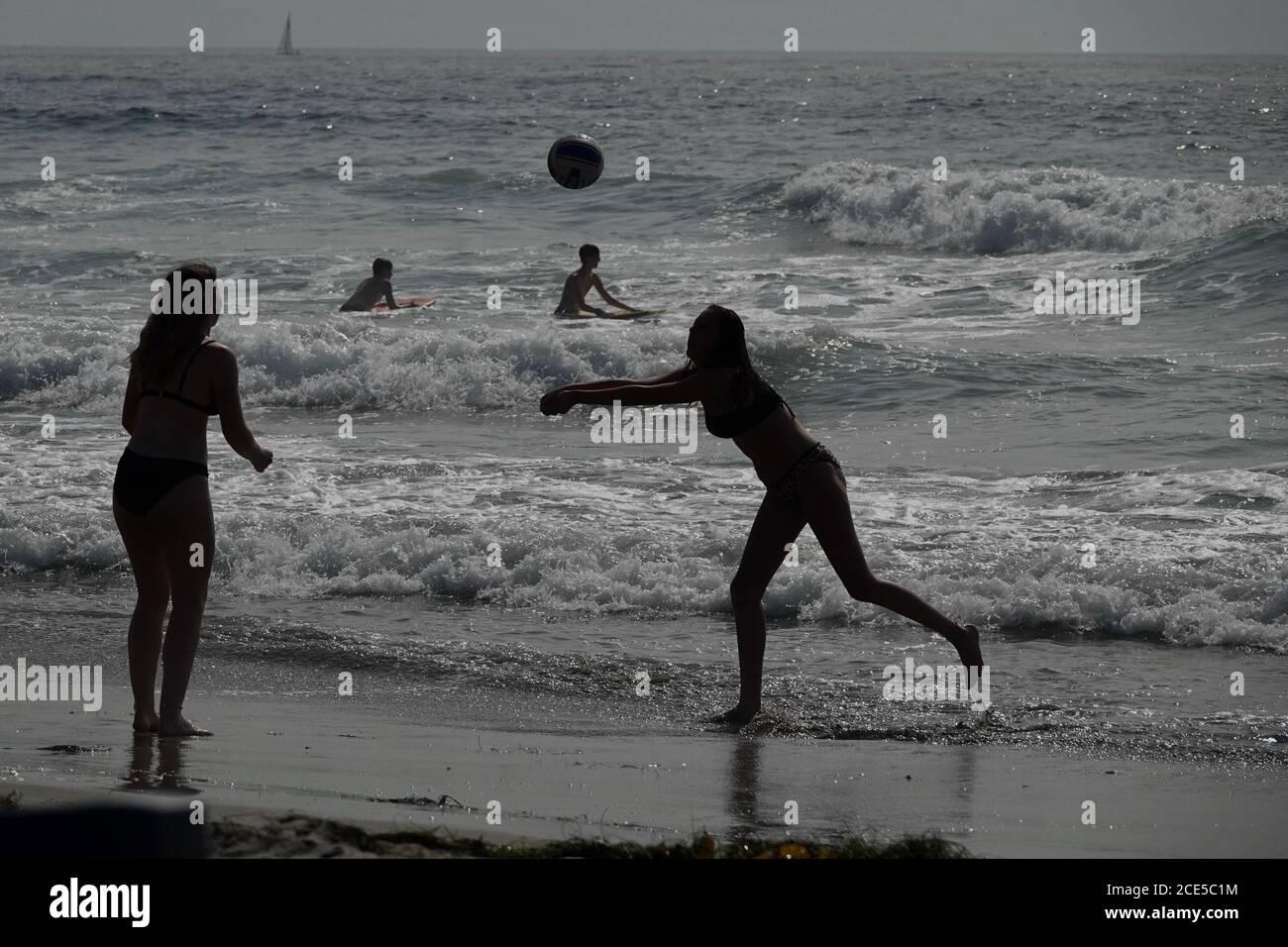 Une silhouette de deux filles jouant au Beach-volley sur le sable près de l'océan. Banque D'Images