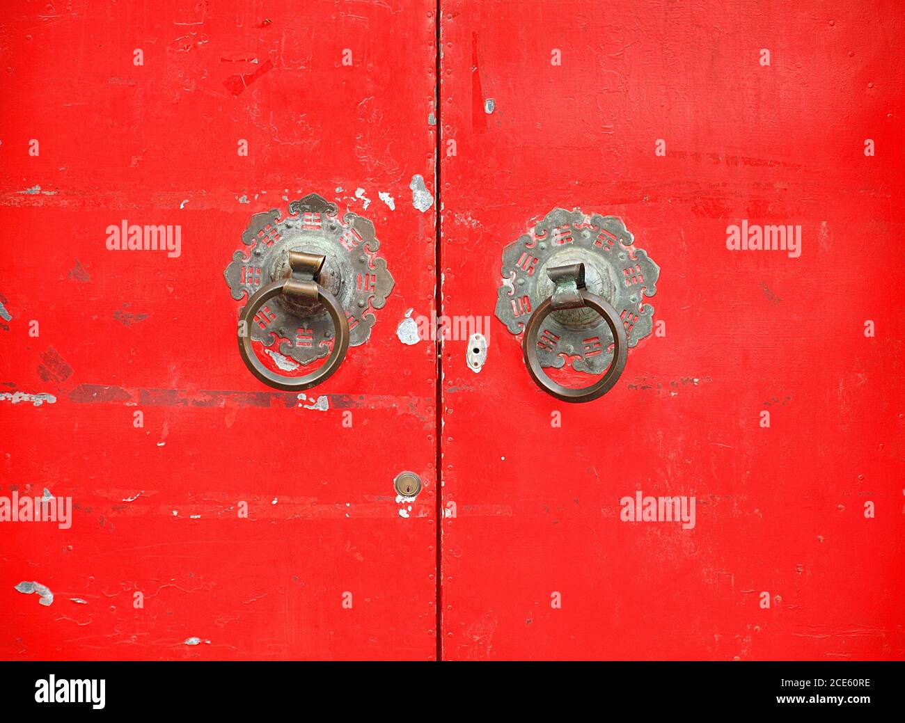 Vieux bronze avec une porte rouge doorknockers qui montrent les symboles taoïstes chinois Banque D'Images