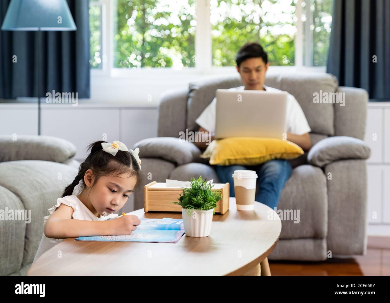 Fille dessin avec papa travaillant à la maison Banque D'Images