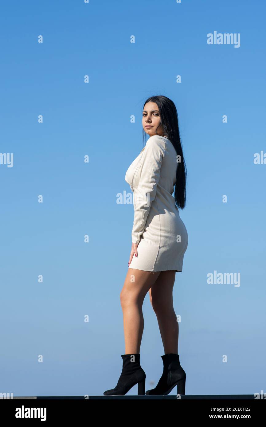 Belle jeune femme portant une robe courte debout à l'extérieur regardant appareil photo Banque D'Images