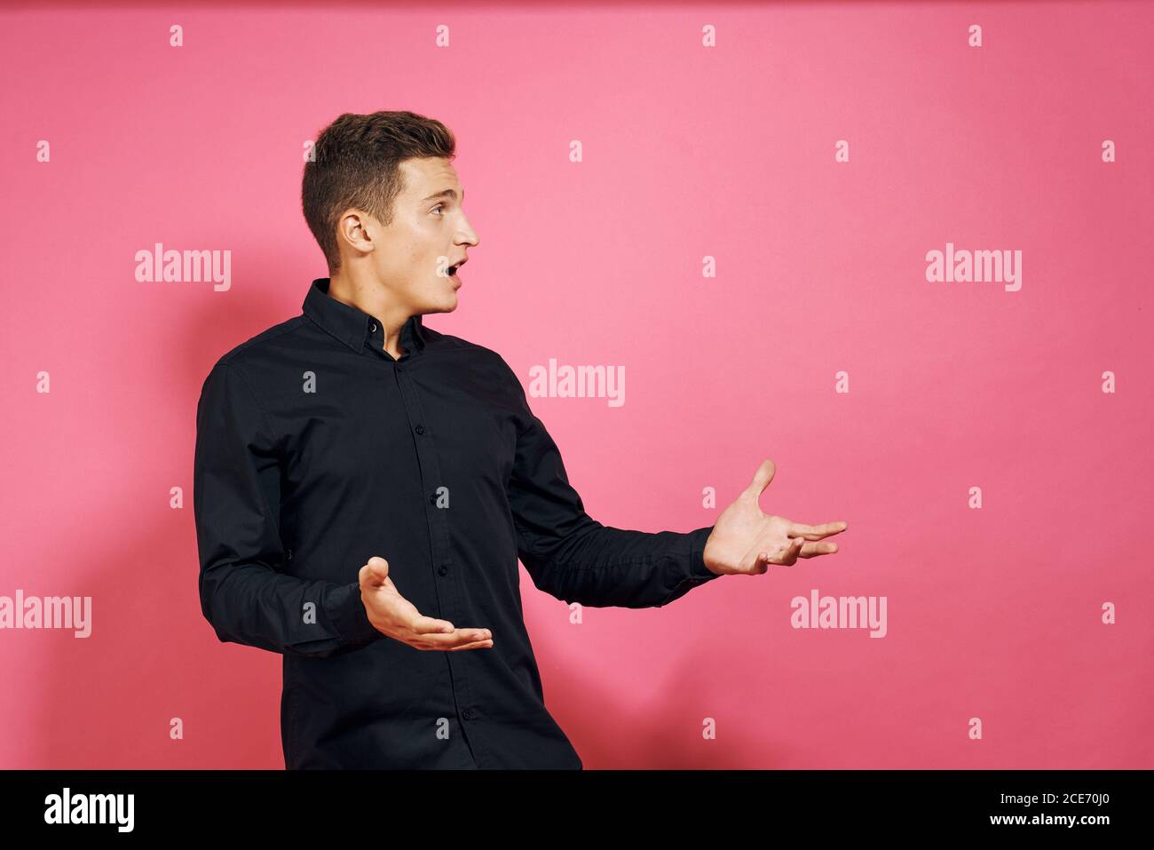 Homme en noir mouvements de chemise avec les mains style de vie rose