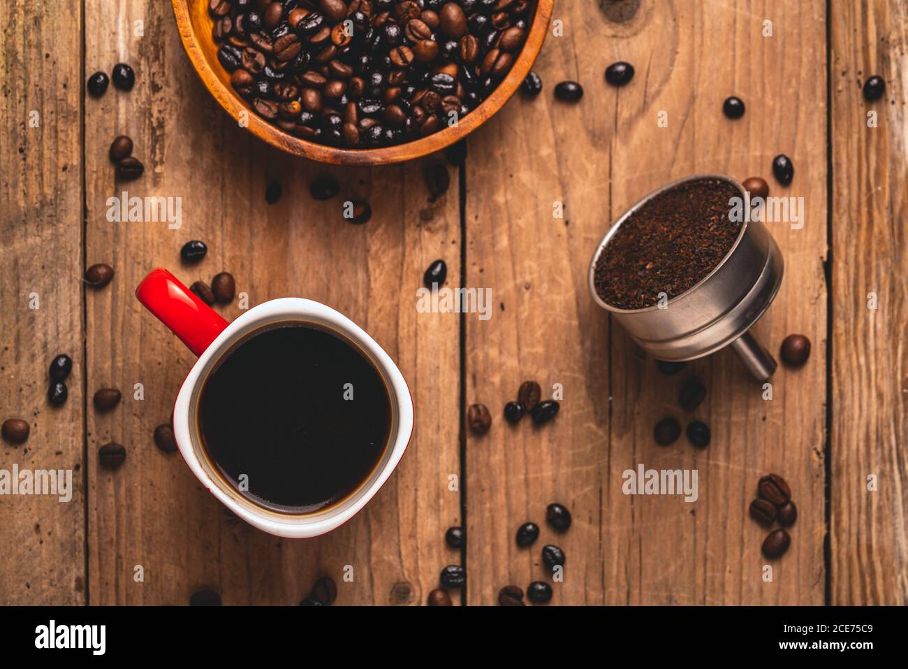 Vue de dessus de la délicieuse boisson dans la tasse placée sur la table avec grains de café et café moulu dans un filtre en métal Banque D'Images