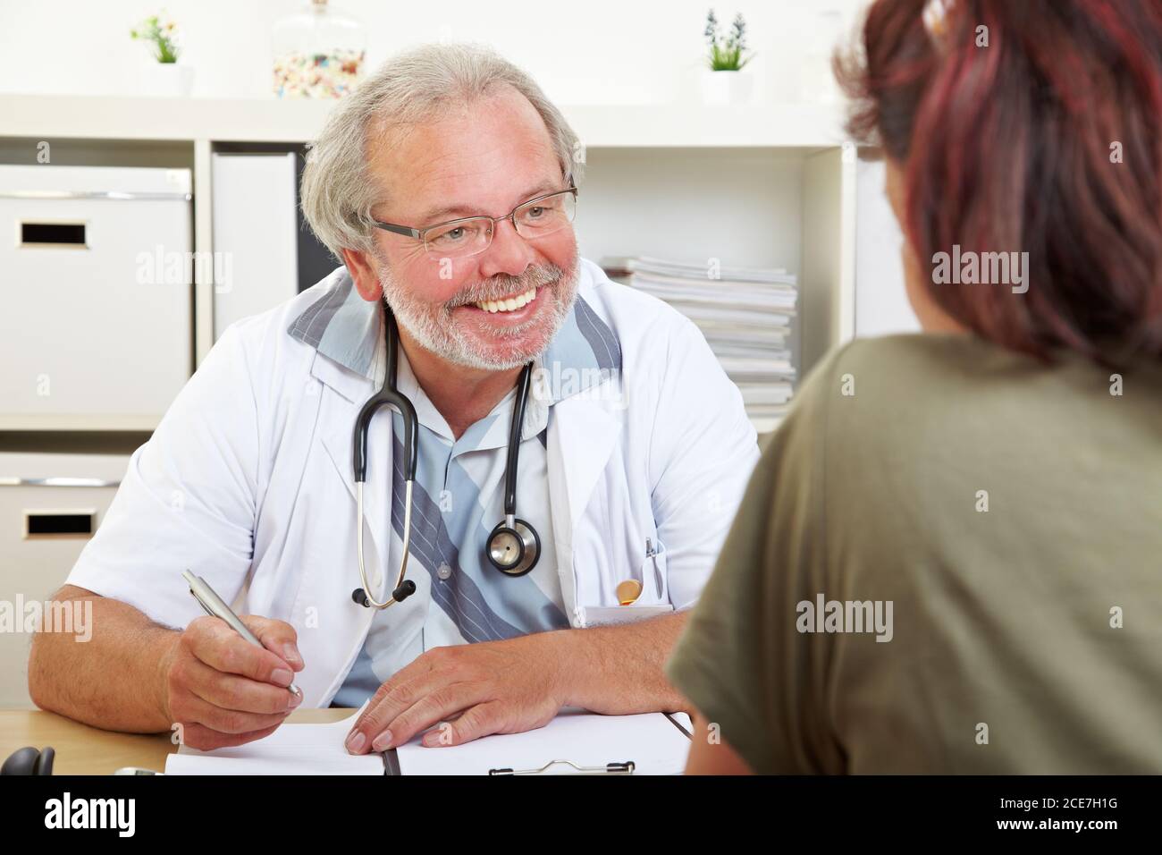 Un médecin amical à la réception dans son cabinet conseille un patient âgé Banque D'Images