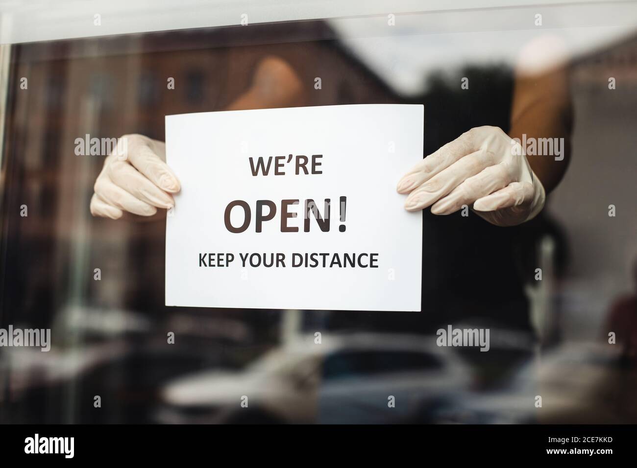 Les petites entreprises sont de nouveau ouvertes. Les femmes mains de maître des ongles raccroche l'avis de distance sociale Banque D'Images