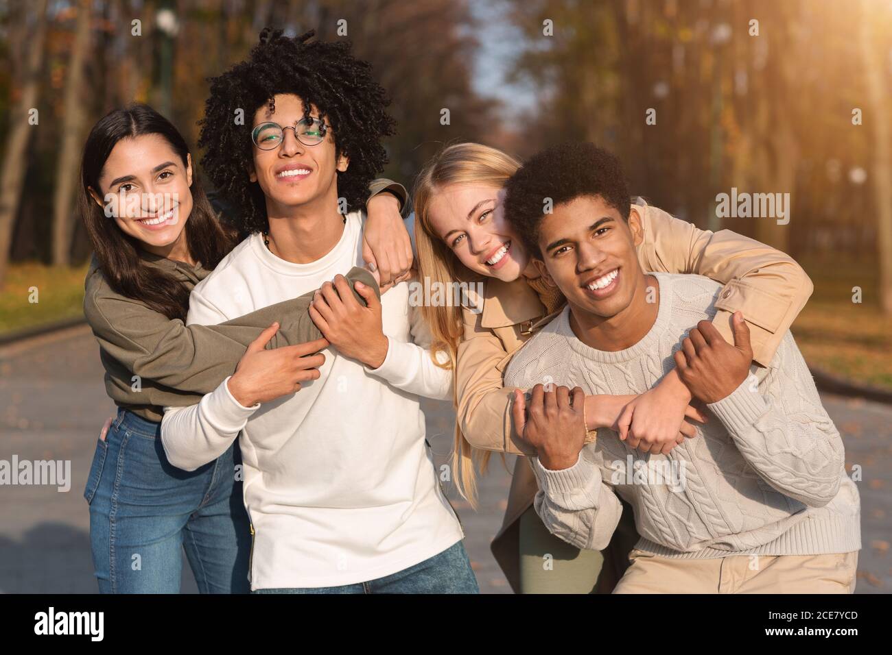 Deux couples de jeunes adolescents multiraciaux se câlinent au parc Banque D'Images