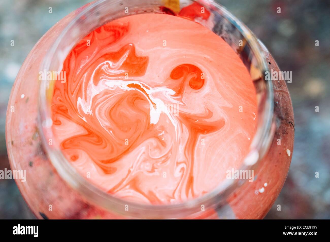 De la peinture ci-dessus dans un pot avec de l'eau colorée au-dessus du plan de travail en studio Banque D'Images