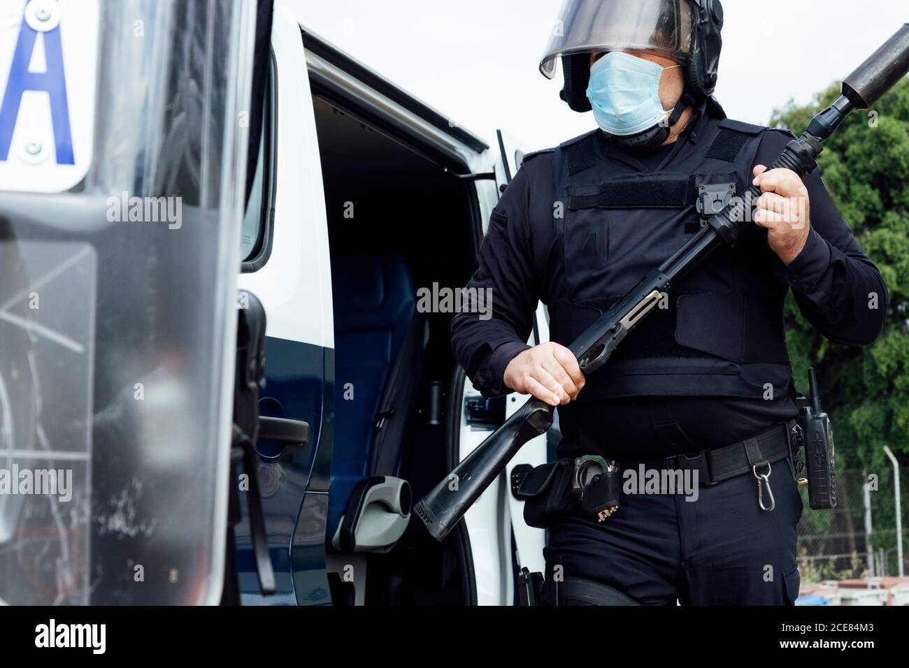 Crop non reconnaissable policier swat dans l'armure de corps de casque et médical masque en cours de fonctionnement avec fusil d'assaut Banque D'Images